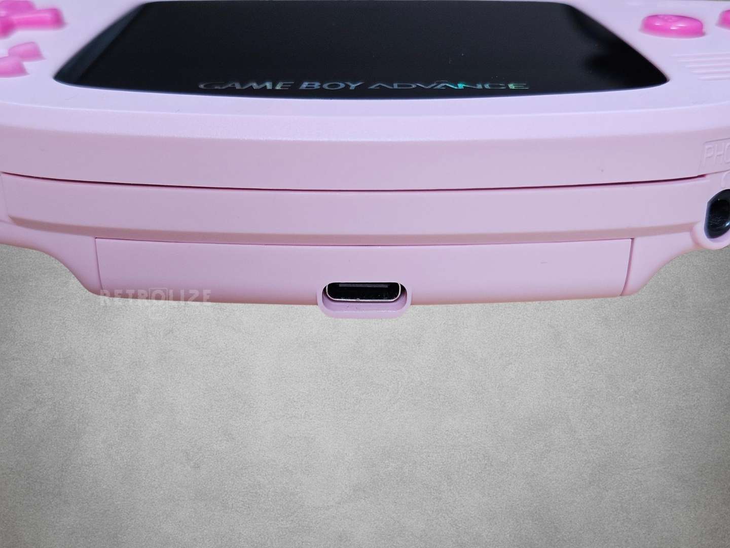 Pink Game Boy Advance with Hot Pink buttons on a grey background usbc view