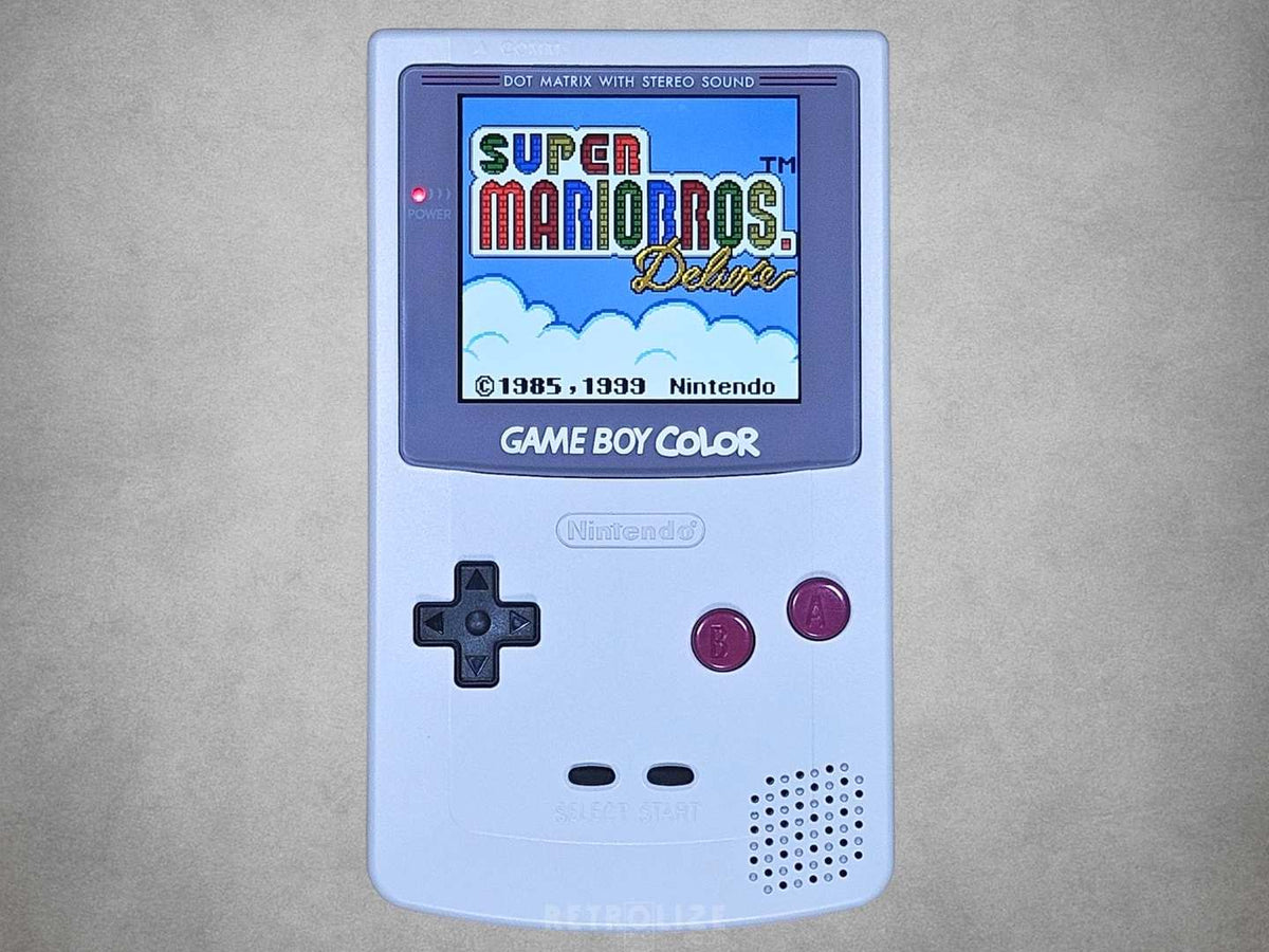 Nintendo Game Boy Color DMG Edition with grey shell, burgundy buttons and IPS screen displaying Super Mario Bros. Deluxe
