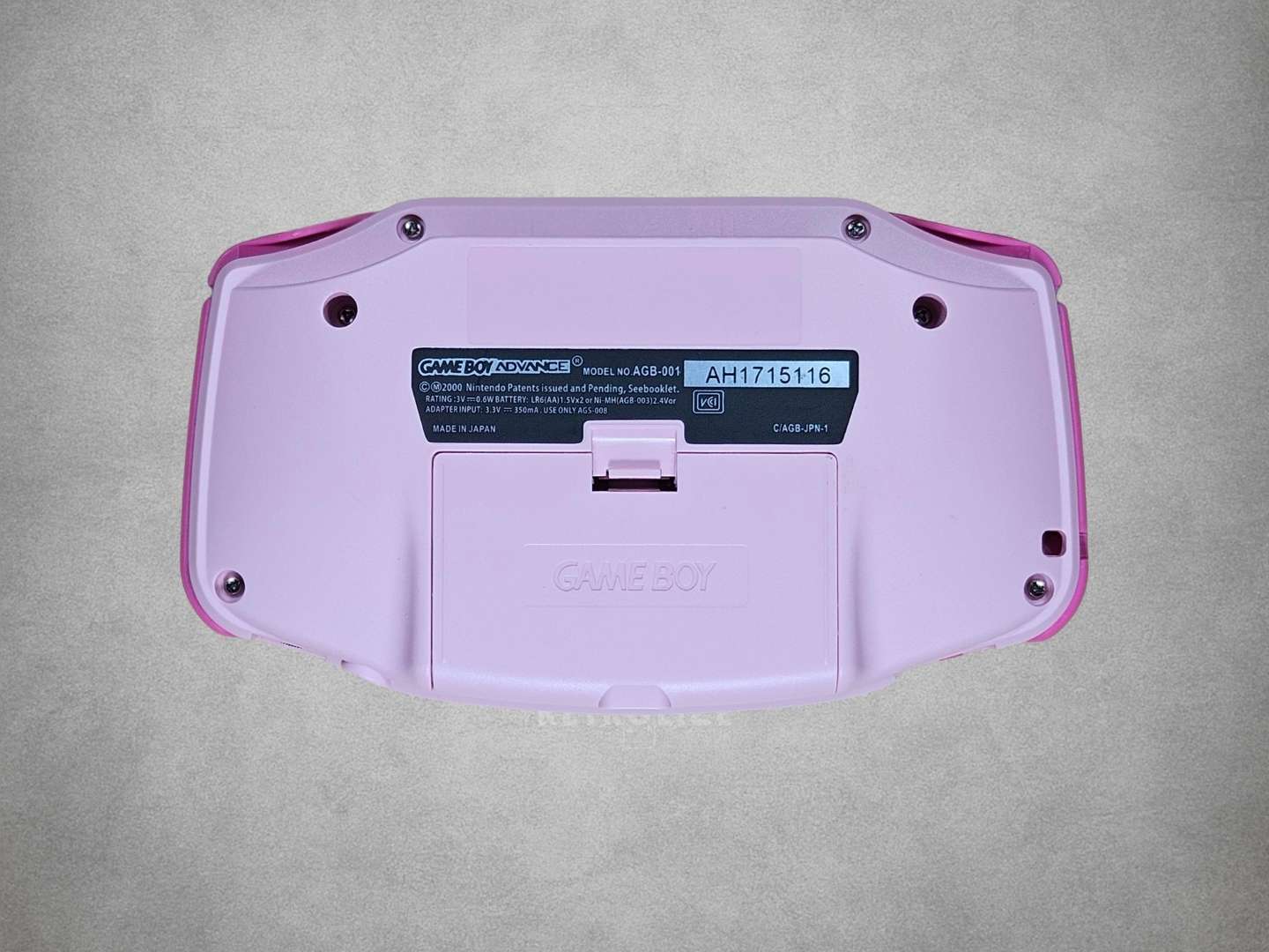Pink Game Boy Advance with Hot Pink buttons on a grey background Back View