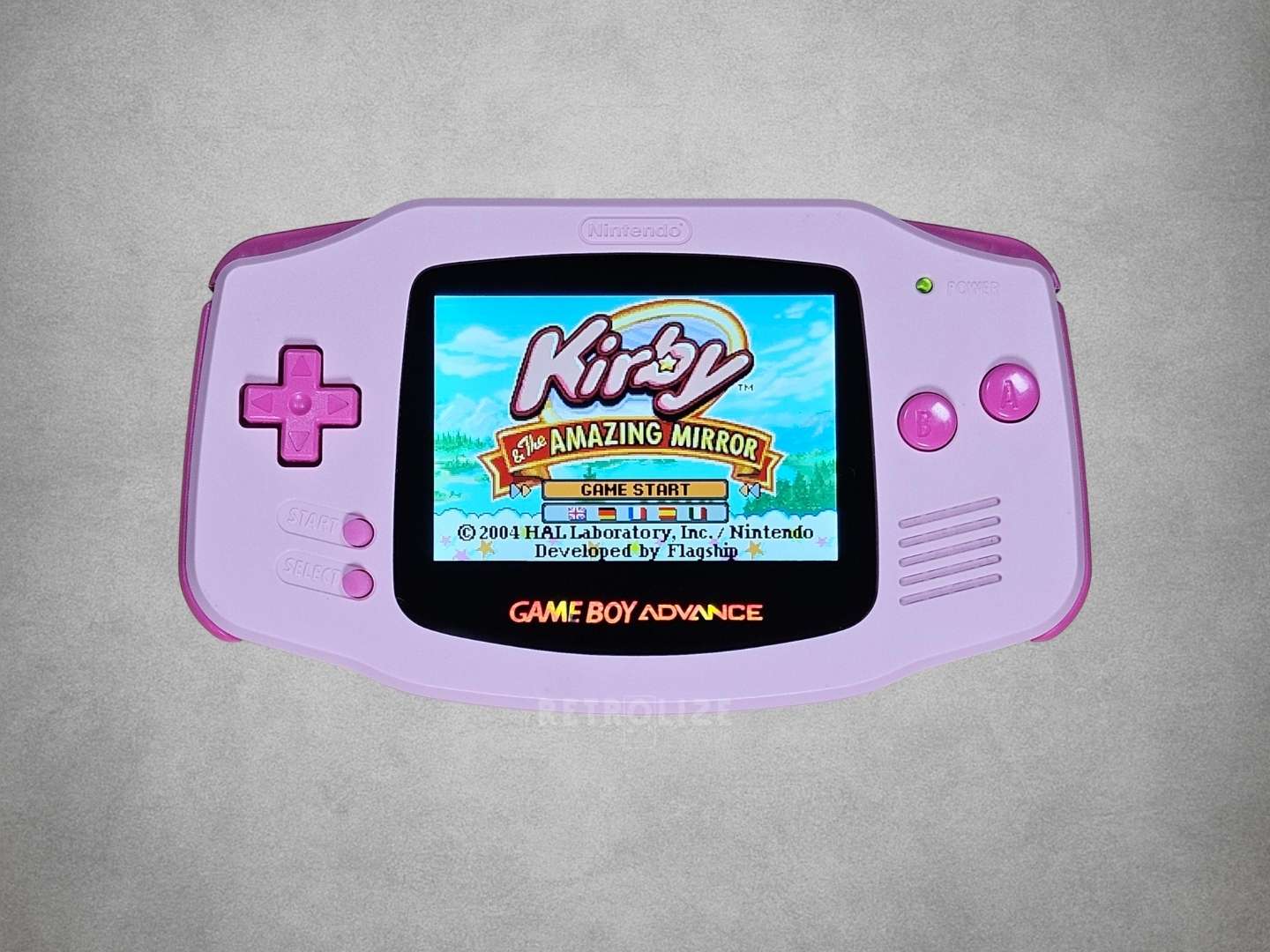 Pink Game Boy Advance with Hot Pink buttons Kirby on screen on a grey background