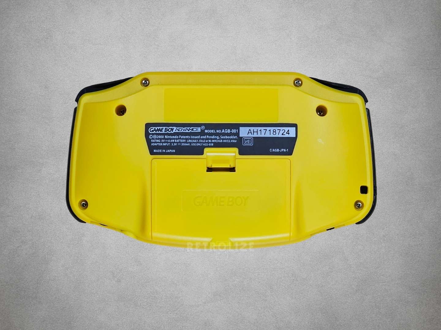 Yellow Game Boy Advance with a label on a grey background