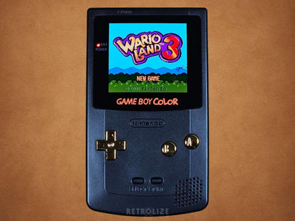 Black Game Boy Color OLED with Metallic Gold Buttons with Wario Land 3 on the Screen