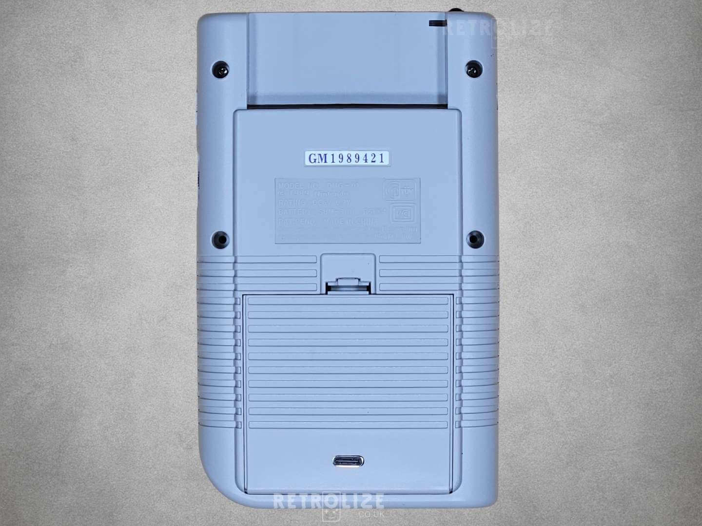 Grey Game Boy DMG-01 rear view showing USBC port off on grey background